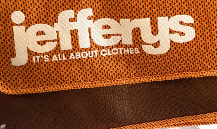 Nahaufnahme des veredelten Jefferys-Logos auf der orangefarbenen Mesh-Struktur des Cooling Towels