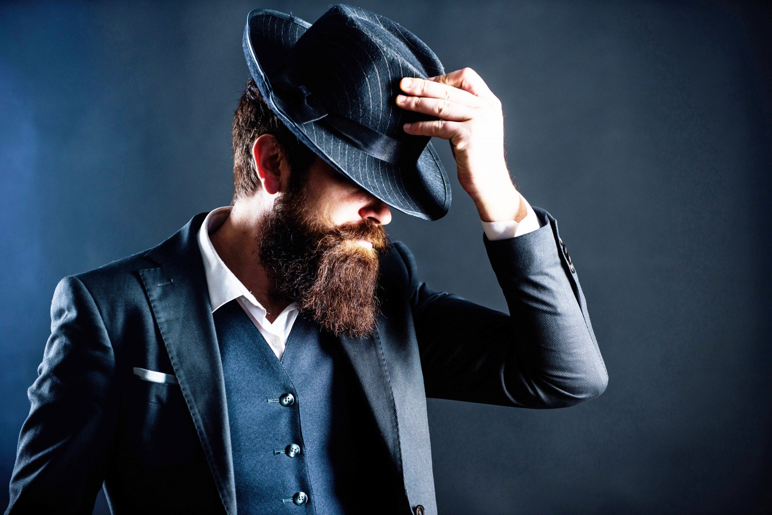 Corporate Fashion Studie Cover. Fein gekleideter Mann mit Hut in dunklem Hintergrund